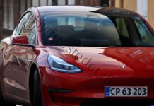 Elbil for begyndere: Hvad sker der under motorhjelmen, og hvad skal du vide før køb? Striking red electric car with headlights on, parked on an urban street.