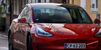 Elbil for begyndere: Hvad sker der under motorhjelmen, og hvad skal du vide før køb? Striking red electric car with headlights on, parked on an urban street.