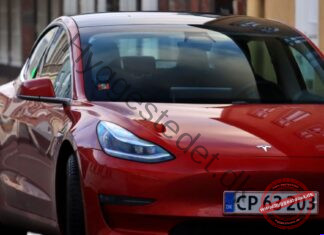 Elbil for begyndere: Hvad sker der under motorhjelmen, og hvad skal du vide før køb? Striking red electric car with headlights on, parked on an urban street.